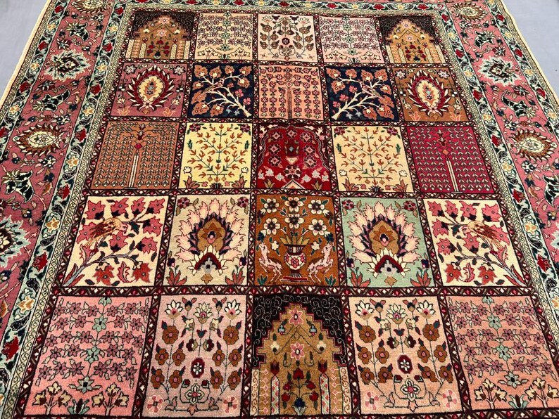 May include: A rectangular area rug featuring a grid of square panels, each decorated with intricate floral, botanical, and architectural motifs in shades of red, pink, cream, brown, and navy blue, framed by a wide, ornate floral border.