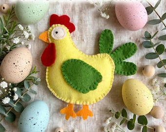 Puede incluir: Un pollo de fieltro amarillo con cresta y barbillas rojas, pico y patas naranjas, y alas y plumas de cola verdes. El pollo presenta puntadas de festón visibles en los bordes. El texto dice Felt Chicken Pattern y PDF Sewing Pattern.