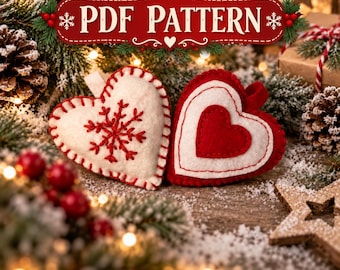 Puede incluir: Dos adornos de corazón de fieltro con una etiqueta PDF PATTERN. Un corazón es blanco con bordado de copo de nieve rojo, el otro es rojo con un centro blanco. Ambos presentan costuras de festón visibles y pequeñas presillas para colgar.