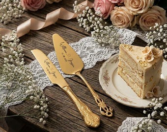Könnte beinhalten: Ein goldfarbenes Tortenmesser- und Heber-Set mit verzierten Griffen, graviert mit dem Text William & Joycen und dem Datum 12.08.2025, platziert neben einem Stück Torte auf einem Teller mit Blumenrand, umgeben von rosa Rosen und Schleierkraut.