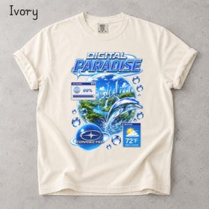 May include: An ivory short-sleeve t-shirt featuring a graphic print with the text "DIGITAL PARADISE". The design includes a chrome dolphin, a 99% loading bar, a weather widget showing 72°F, and a blue "CONNECTED" logo with a star emblem.