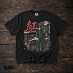 Op de afbeelding: Een zwart t-shirt met een grafische print van een persoon die in de regen onder een volle maan achter een witte sportwagen staat. Het ontwerp bevat rode Japanse kanji-tekens, de tekst RED LINE RACER en aanvullend Japans schrift.