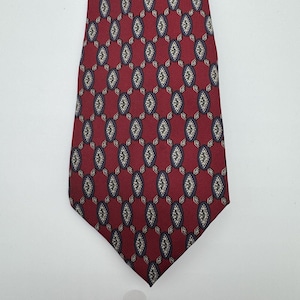May include: A necktie featuring a deep red background with a repeating pattern of dark blue oval shapes. Each oval contains a smaller, intricate geometric diamond design in white and gold tones, connected by thin lines to form a structured grid.