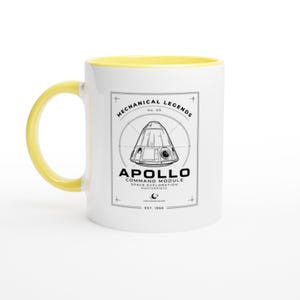 May include: A white ceramic mug with a bright yellow handle and interior rim. The front features a black line drawing of an Apollo command module inside a rectangular frame with the text Mechanical Legends, Apollo Command Module, and Est. 1966.