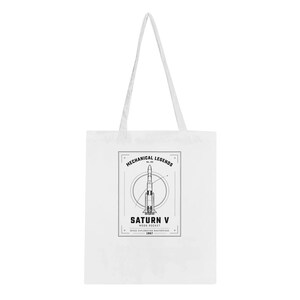 Könnte beinhalten: Eine weiße Tragetasche mit einem schwarzen Grafikdruck einer Saturn V-Rakete. Das Design enthält den Text "MECHANICAL LEGENDS", "SATURN V", "MOON ROCKET", "SPACE EXPLORATION MASTERPIECE" und "1967" innerhalb eines rechteckigen Rahmens.