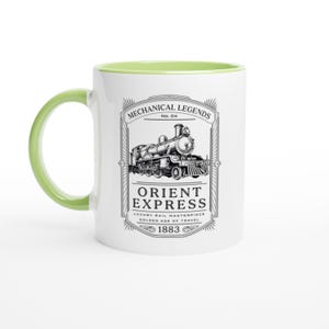 May include: A white ceramic mug with a light green handle and interior rim. The front features a black graphic of a steam locomotive inside a decorative frame with the text: MECHANICAL LEGENDS No. 04 ORIENT EXPRESS LUXURY RAIL MASTERPIECE GOLDEN AGE OF TRAVEL 1883.