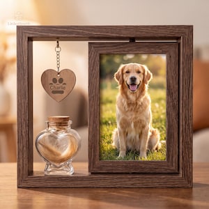 May include: A dark wood frame containing a vertical photo of a golden retriever sitting in grass. A heart-shaped wooden tag hangs from the top, engraved with a paw print and the name Charlie. A heart-shaped glass jar with a cork lid sits below.