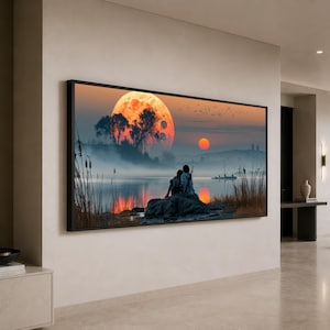 Puede incluir: Un cuadro rectangular con marco negro que muestra un paisaje con una gran luna naranja, un sol más pequeño y dos figuras sentadas sobre una roca junto a un lago brumoso. Juncos altos crecen en primer plano y aves vuelan en el cielo.