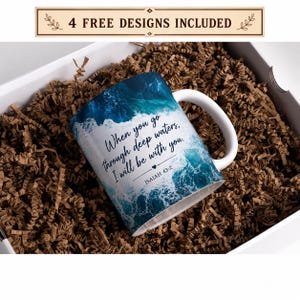 May include: A white ceramic mug featuring a vibrant blue ocean wave print and the black text, When you go through deep waters, I will be with you. ISAIAH 43:2, with a small heart icon. The mug has a curved handle and is positioned at an angle.