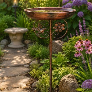 Peut inclure: Un bain d'oiseaux de couleur cuivre doté d'un bassin circulaire soutenu par un piquet métallique unique. Le support est orné d'un colibri en métal et d'un motif floral, tous deux intégrés à la structure sous le bassin.