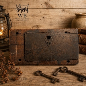 May include: A rectangular, weathered brown wooden block featuring a central dark metal plate with a diamond-shaped keyhole cutout. Two antique-style metal skeleton keys lie in the foreground, accompanied by a vintage lantern and books.