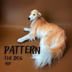 May include: A plush toy dog with long, flowing white and light tan fur, lying down in a relaxed position. The text "PATTERN THE DOG PDF" is printed in black letters on the left side of the image, indicating a digital sewing or craft pattern.