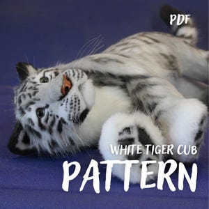 Könnte beinhalten: Ein weißes Tigerbaby-Stofftier mit schwarzen Streifen, einer rosa Nase und dunklen Augen, das auf dem Rücken liegt. Der Text PDF, WHITE TIGER CUB und PATTERN ist in Weiß über das Bild gedruckt und weist auf eine digitale Nähanleitung hin.