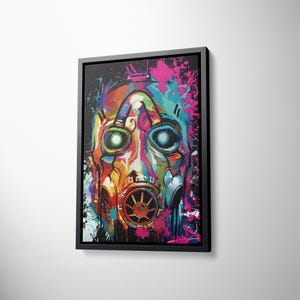 May include: A framed wall art print featuring a vibrant, multi-colored gas mask illustration. The artwork uses a graffiti-style aesthetic with splashes of pink, blue, yellow, and orange paint against a dark background, encased in a black frame.