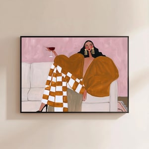 May include: A framed painting depicts a person with dark hair and gold earrings sitting on a white sofa. The person wears a large mustard-colored top and a white and mustard checkered skirt, holding a glass of red wine against a pink background.