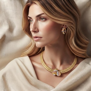 Può includere: Una collana girocollo dorata caratterizzata da una fascia testurizzata a intreccio con un nodo centrale contenente piccole pietre multicolori. Orecchini a lobo abbinati a forma di nodo con dettagli in pietre multicolori sono indossati.