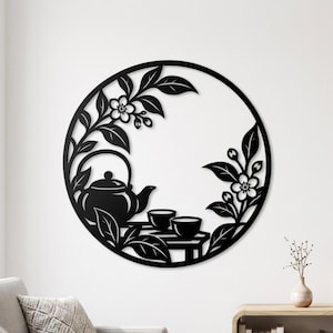 May include: A circular black metal wall art piece featuring a silhouette design of a teapot and two small cups resting on a table, surrounded by leafy branches with blossoms. The intricate cutout pattern creates a detailed botanical scene.