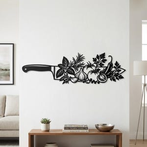 以下が含まれることがあります： 大きなシェフナイフの形をした黒い金属製のウォールアート。刃のシルエットには、ニンニク、トマト、唐辛子など、さまざまな新鮮なハーブや野菜の複雑な切り抜きデザインが組み込まれています。