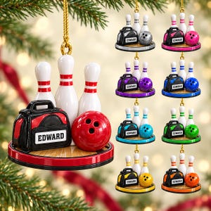 May include: A bowling-themed Christmas ornament featuring three white pins, a bowling ball, and a black bowling bag with the name EDWARD printed on a white label. The ornament sits on a circular base and hangs from a gold cord.