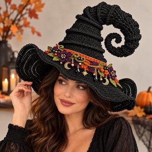 May include: A black crocheted witch hat featuring a tall, curled point and a wide brim. The hat is decorated with an orange band, purple fabric flowers, green leaves, orange berries, and gold-toned charms including crescent moons and stars.