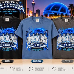 Könnte beinhalten: Drei kurzärmelige T-Shirts in Schwarz, Blau und Pfeffergrau, jeweils mit einer Grafik von fünf Personen in Anzügen und dem Text INTO THE MILLENNIUM LIVE AT THE SPHERE LAS VEGAS 2026. Eine schwarze Baseballkappe mit dem Text LAS VEGAS ist abgebildet.