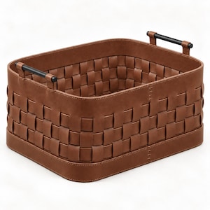 May include: A rectangular storage basket featuring a woven brown leather-like exterior with a solid base and two black cylindrical handles attached to the top rim with brown leather tabs. The basket has a structured shape and visible stitching.