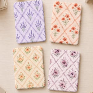 May include: Four rectangular notebooks with rounded corners, each featuring a distinct floral pattern arranged in a diamond grid. The designs include purple lavender, orange poppies, peach roses, and purple anemones on light-colored backgrounds.