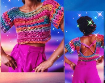 Peut inclure: Un haut en crochet arc-en-ciel avec un dos croisé. Le haut est court et a des manches courtes. Le mannequin porte le haut avec un pantalon rose.