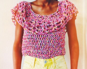 Pode incluir: Um top de crochê com um esquema de cores rosa, roxo e laranja. O top tem um decote largo e com babados e mangas curtas.