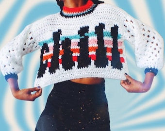 May include: A white crocheted sweater with a colorful striped design and the word "JAIL" in black lettering.