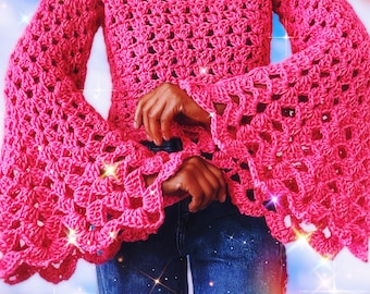 Peut inclure: Un haut en crochet rose avec des manches bouffantes. Le haut est de style court et a une coupe ample.