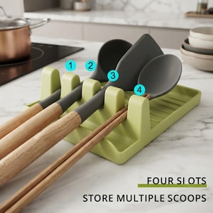 May include: A light green kitchen utensil rest with four slots for holding cooking tools. The tray features a ribbed surface and is shown holding three dark gray silicone utensils and a pair of wooden chopsticks. Text reads FOUR SLOTS STORE MULTIPLE SCOOPS.