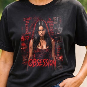 May include: A black short-sleeved t-shirt featuring a graphic print of a person with long dark hair in a red corset. The text reads I LOVE YOU SO SO SO MUCH, BE CAREFUL WHO YOU WISH FOR, and OBSESSION, accompanied by small red heart icons.