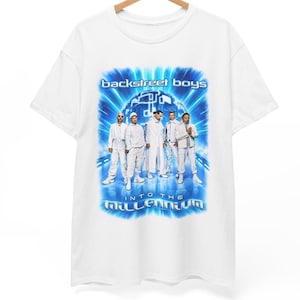 Peut inclure: Un t-shirt blanc à manches courtes avec une impression graphique des Backstreet Boys. Le motif inclut le texte "backstreet boys" et "INTO THE MILLENNIUM" sur un fond bleu futuriste lumineux avec les cinq membres du groupe en tenues blanches.
