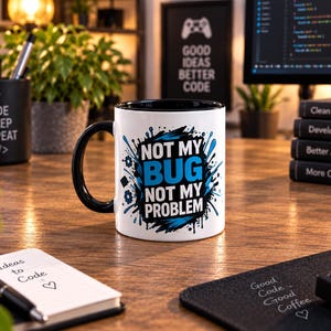Könnte beinhalten: Ein weißer Keramikbecher mit schwarzem Henkel und schwarzem Innenraum, verziert mit einem blau-schwarzen Grafikdesign und dem Text "NOT MY BUG NOT MY PROBLEM" in fetter Schrift, umgeben von Farbspritzern und kleinen zahnradartigen Symbolen.
