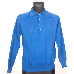May include: A long-sleeved, bright blue polo shirt with a collared neckline and three white buttons. The shirt has vertical, textured detailing and ribbed cuffs and hem. The shirt is displayed on a black mannequin.