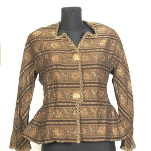 Peut inclure: Veste marron à motifs avec garniture et boutons dorés. La veste présente un motif cachemire avec des rayures horizontales et une taille basque. Le col et les poignets sont ornés de détails dorés, et la veste est boutonnée.