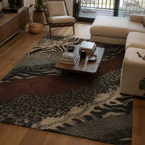May include: A rectangular area rug featuring a patchwork design of animal print patterns including zebra stripes and leopard spots in shades of black, gray, beige, and deep red, covering the floor beneath a wooden coffee table in a living room.