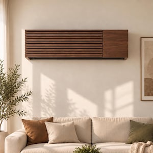 May include: A rectangular wall-mounted cover for an air conditioning unit, constructed from dark brown wood. The design features a series of horizontal slats across the left side and a solid, smooth wooden panel on the right side of the unit.