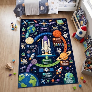 May include: A rectangular area rug featuring a dark blue space-themed design with a central space shuttle, planets, astronauts, satellites, and rockets. The rug includes eight numbered educational activity prompts with text like Match, Find, and Count.