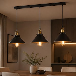 Puede incluir: Una lámpara de techo lineal con tres pantallas cónicas de metal negro mate suspendidas de una base rectangular negra. Cada pantalla incluye un casquillo de tono latón y una bombilla de filamento expuesta hacia abajo.