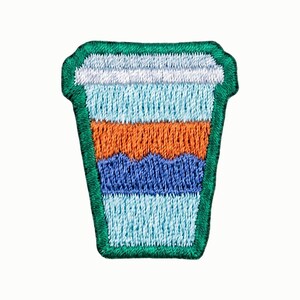 May include: An embroidered patch shaped like a disposable coffee cup with a lid. The design features horizontal bands of white, light blue, orange, dark blue, and light blue, all outlined with a thick, dark green stitched border.