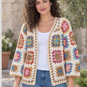May include: A crochet cardigan featuring a multi-coloured granny square pattern. The garment is constructed from cream-coloured yarn squares accented with blue, pink, brown, and orange centres. It has an open front, three-quarter length sleeves, and a cream-coloured border along the edges.