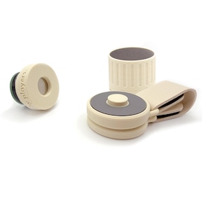 May include: A set of cream-coloured plastic accessories including a small circular piece with the text "by players" embossed on the side, a cylindrical cap, and a circular component with a central button attached to a folded cream strap.