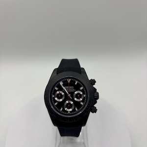 May include: A black Seiko chronograph wristwatch featuring a black dial with three sub-dials, silver-toned hour markers, and a red second hand. The watch has a black bezel with a tachymeter scale, a black case, and a black silicone rubber strap.