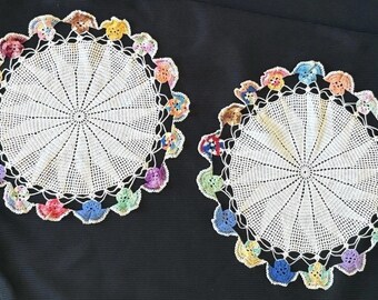 Juego vintage de 2 tapetes redondos blancos tejidos a mano con borde floral multicolor.
