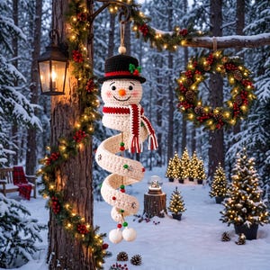 Op de afbeelding: Een gehaakte sneeuwpop-ornament met een zwarte hoed, oranje neus en een lang, spiraalvormig wit lichaam gewikkeld in een rood-wit gestreepte sjaal. De sneeuwpop is versierd met kleine houten sneeuwvlokken en rode en groene kralen langs de lengte.