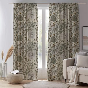 May include: Two floor-length curtains hanging from a rod, featuring a repeating botanical pattern of muted green thistle-like flowers and slender stems on a light cream background. The fabric is semi-sheer, allowing soft light to filter through.