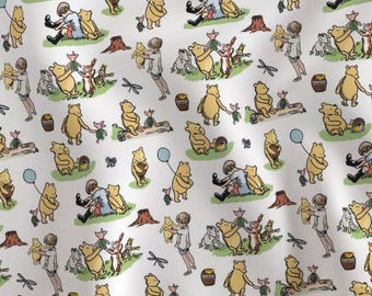 Op de afbeelding: Witte stof met een herhalend patroon met Winnie de Poeh en zijn vrienden. De illustraties bevatten Poeh, Knorretje, Janneman Robinson en andere personages in verschillende scènes. Het ontwerp bevat honingpotten, ballonnen en vlinders.