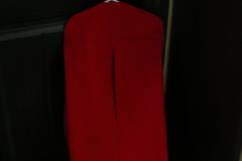 Peut inclure: Un sac de v&ecirc;tement rouge avec une fermeture &eacute;clair. Le sac est suspendu &agrave; un cintre.